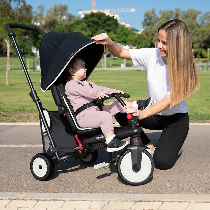 mother getting her daughter ready in the stroller in a park