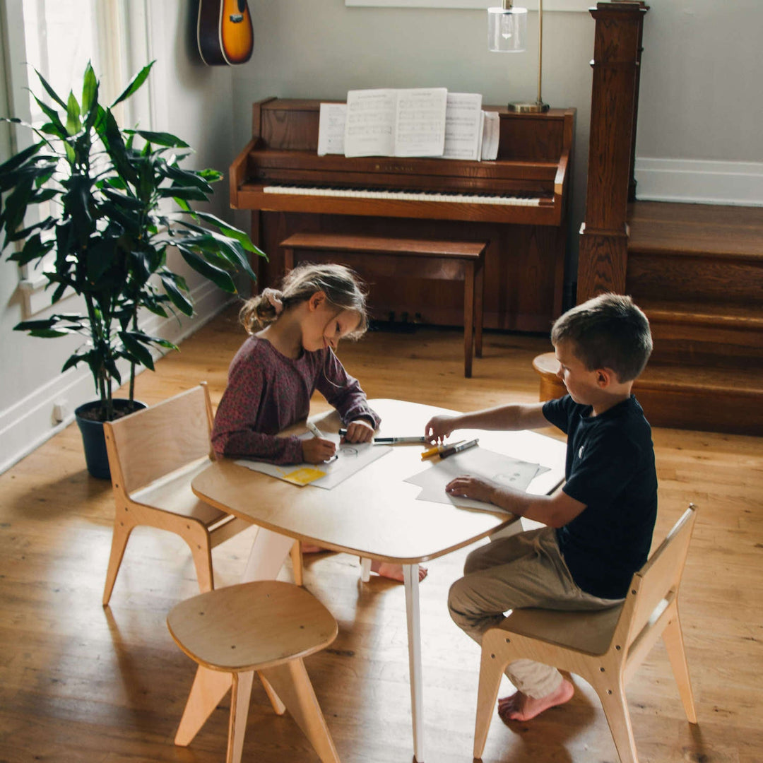 two kids playing on a montessori table and chair set