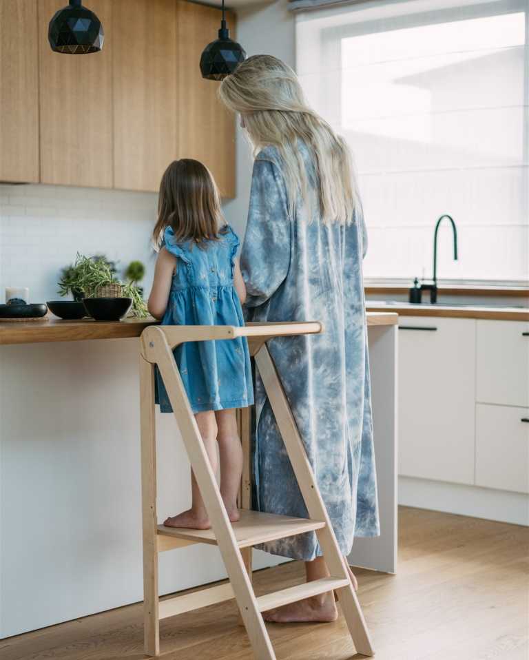 Toddler helping her mother in the kitchen using a kitchen helper stool