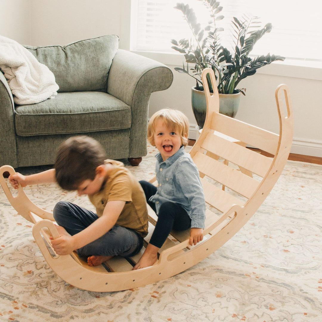 two kids balancing on a wooden rocker arch